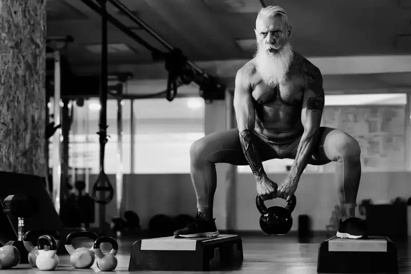 elderly male bodybuilder lifting heavy weights in gym after regenerative therapy